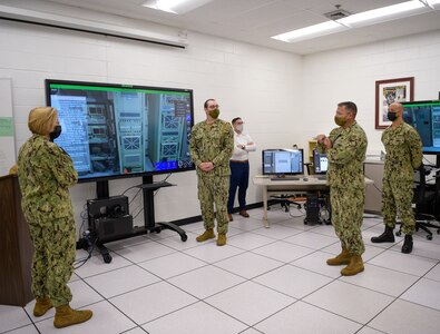 During the tour for Vice Adm. Kelly Aeschbach, commander, Naval Information Forces (left), Capt. Marc Ratkus, commander, Center for Information Warfare Training (right), commented on the cost savings of using the Multipurpose Reconfigurable Training Systems (MRTS) 3D trainers during the demonstration of the AN/SLQ-32 (V)6 MRTS by Cryptologic Technician Technical 1st Class Zachery Oconnor, maintenance course supervisor for the AN/SLQ-32 (V)6 (center).