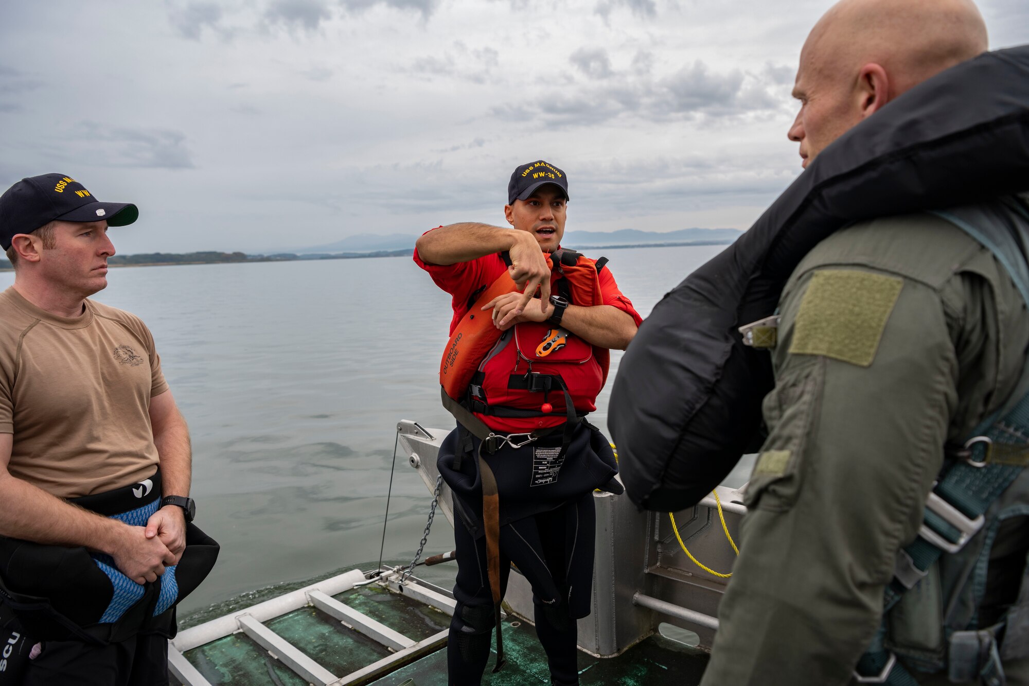 Military members stand on a boat in the water talking.