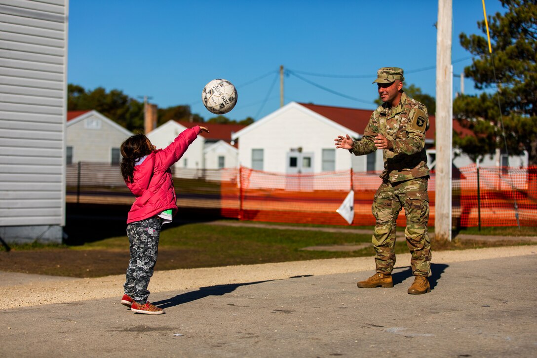 A soldier plays catch with an Afghan child