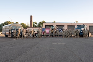 Airmen posing for group photo in front of vehicles and heavy equipment