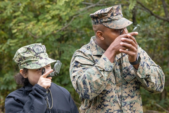 U.S. Marine Corps 1st Lt. Amos R. Mason, Head of Naval Enlisted Programs, guides a naval sea cadet on how to properly use a compass at Marine Corps Base Quantico, Oct. 23, Va. Marine Corps Recruiting Command volunteered to provide mentorship and training during the U.S. Naval Sea Cadet Corps' three-day field training exercise.
