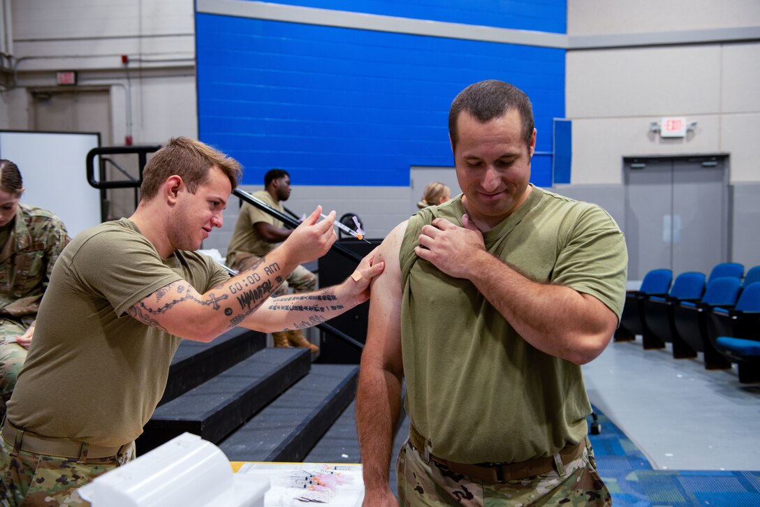 An Airman administers a vaccine to another Airman