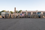 Airmen posing for group photo in front of vehicles and heavy equipment