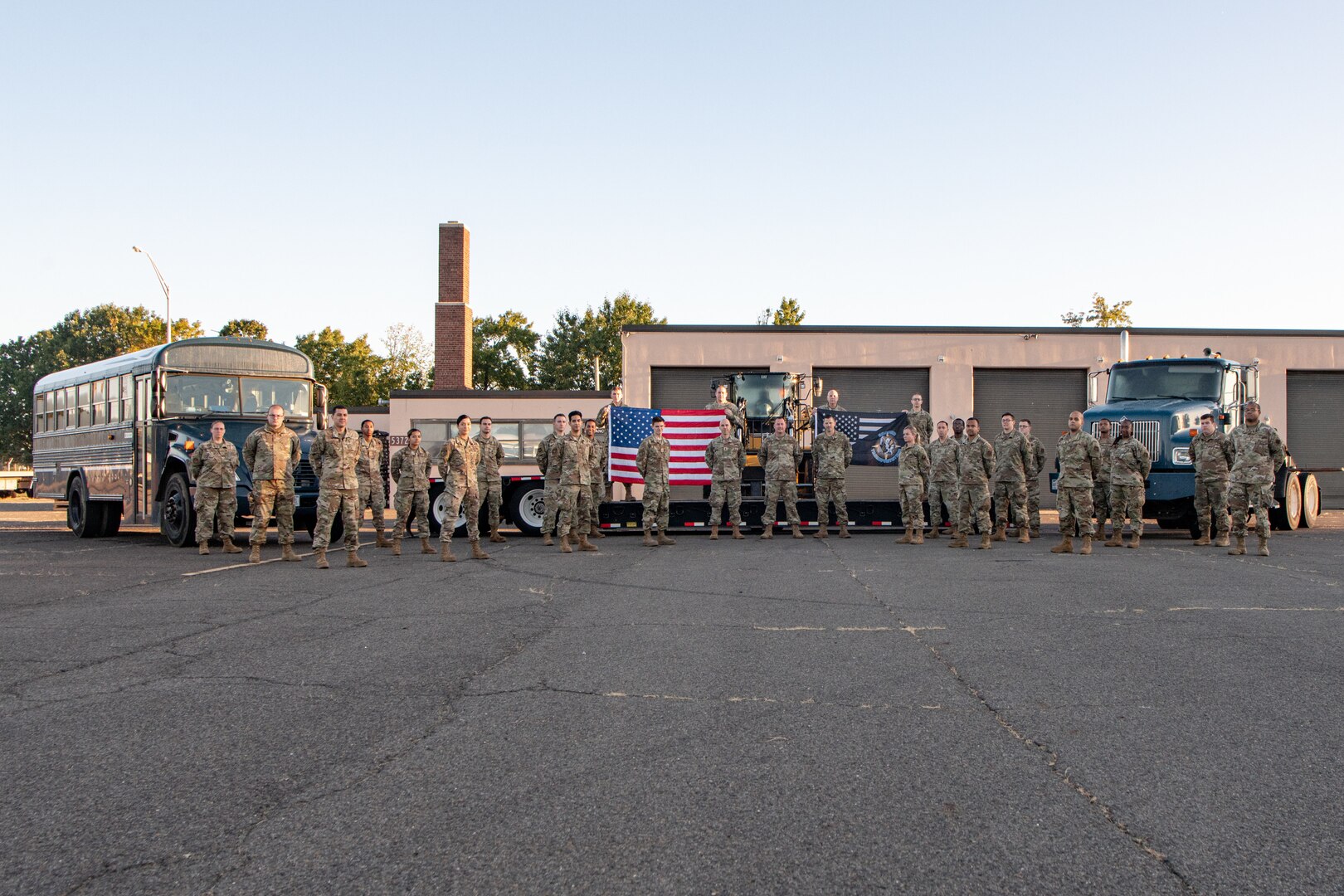 Airmen posing for group photo in front of vehicles and heavy equipment