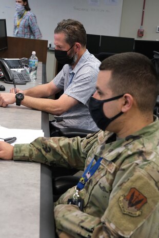 photo two men wearing masks work on computers