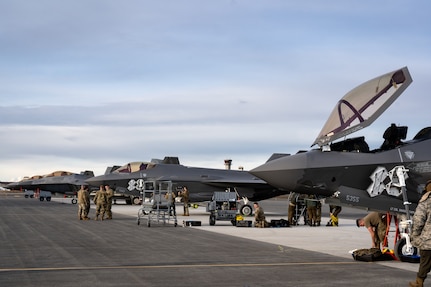 Two F-35A Lightning II aircraft stand alongside three F-22 Raptors.