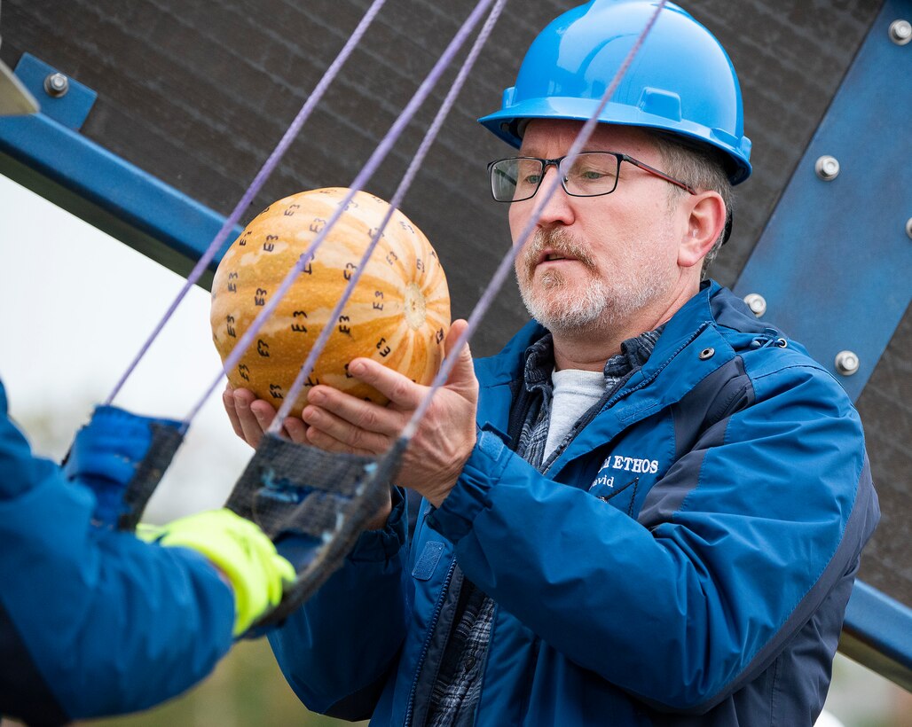 David Mollenhauer, Air Force Research Laboratory, loads a pumpkin into the Team ETHOS catapult Oct. 22, 2021, during the 16th Annual Pumpkin Chuck at Wright-Patterson Air Force Base, Ohio. The pumpkin was marked with “E3” all over its shell so officials would know which team made the shot when pieces of it were found a half-mile away. (U.S. Air Force photo by R.J. Oriez)