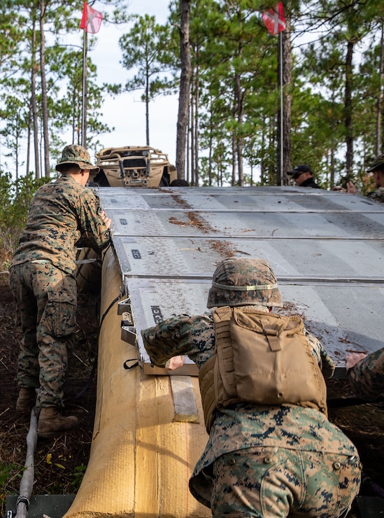 U.S. Marines with Engineer Platoon, 1st Battalion, 2d Marine Regiment, 2d Marine Division, adjust panels on an AirBeam Light-Weight Expeditionary Bridge during Expeditionary Military Trails Project at Camp Lejeune, N.C., Oct. 28, 2021. The Marines utilized the newly-fielded equipment gaining proficiency in constructing combat expedient roads and providing obstacle clearance for moving troops and logistics throughout a contested environment. (U.S. Marine Corps photo by Lance Cpl. Reine Whitaker)