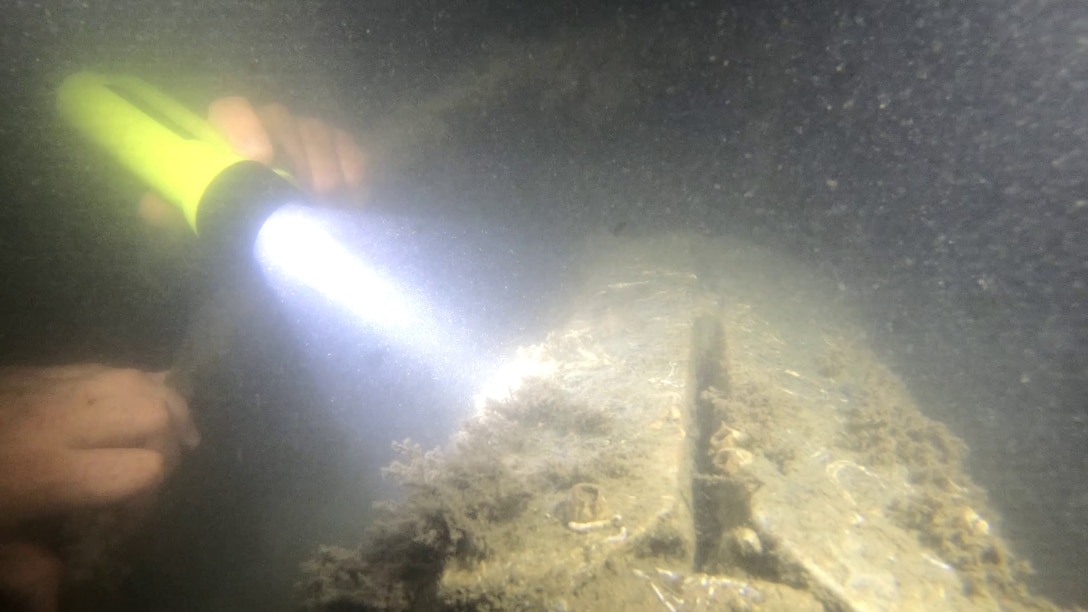 Divers inspect the after end of the aircraft’s cockpit