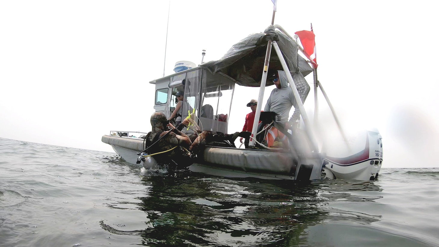 NAVOCEANO hydrographer Billy Hauer enters the water with survey gear.