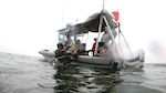 NAVOCEANO hydrographer Billy Hauer enters the water with survey gear.