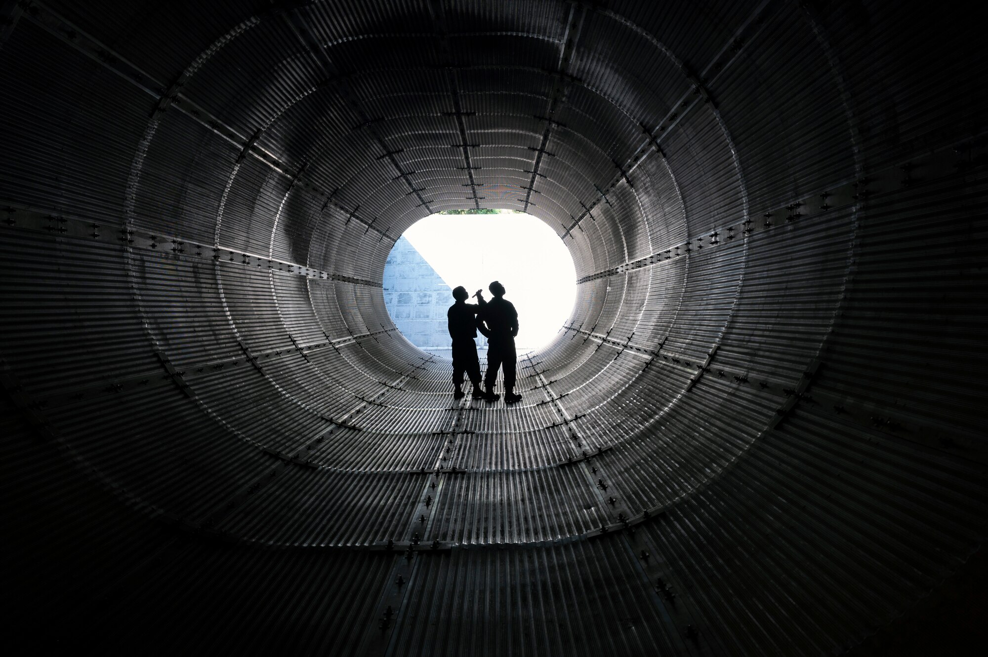 Airmen inspect the inside of an exhaust tube for damage after an engine run.