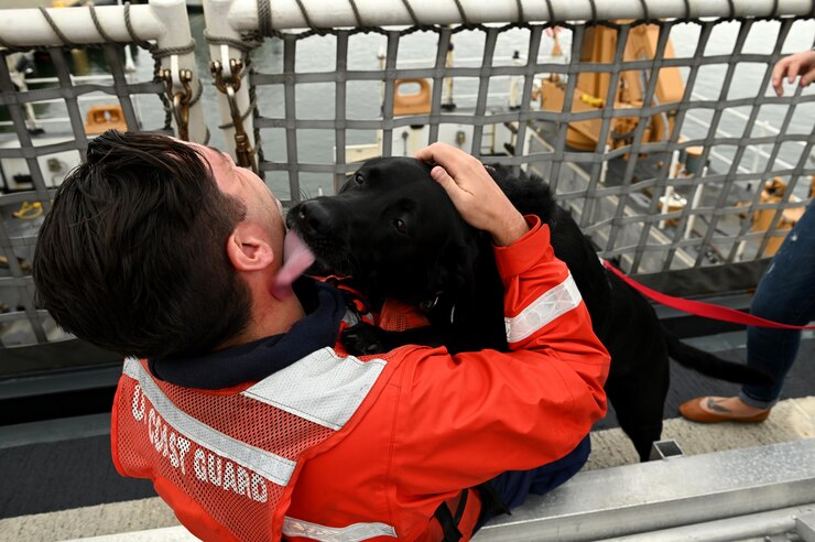 Coast Guard Cutter Munro (WMSL 755) crewmember Petty Officer 2nd Class Kurt Chlebek, a boatswains mate, is greeted by his dog after Munro returned to their homeport in Alameda, California, Oct. 20, 2021, following a 102-day, 22,000 nautical mile multi-mission deployment. Munro’s crew departed Alameda in July for a Western Pacific patrol and operated in support of United States Indo-Pacific Command, which oversees military operations in the region. U.S. Coast Guard photo by Chief Petty Officer Matt Masaschi.