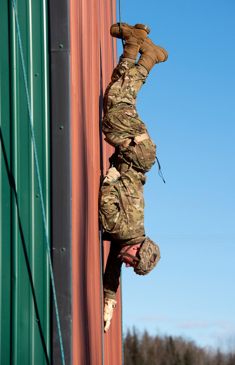 A soldier crawls down a wall.