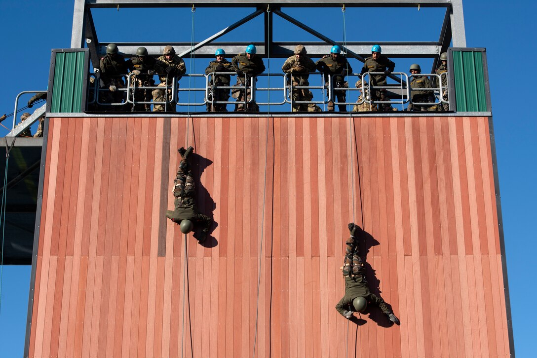 Two soldiers slither down a rope.