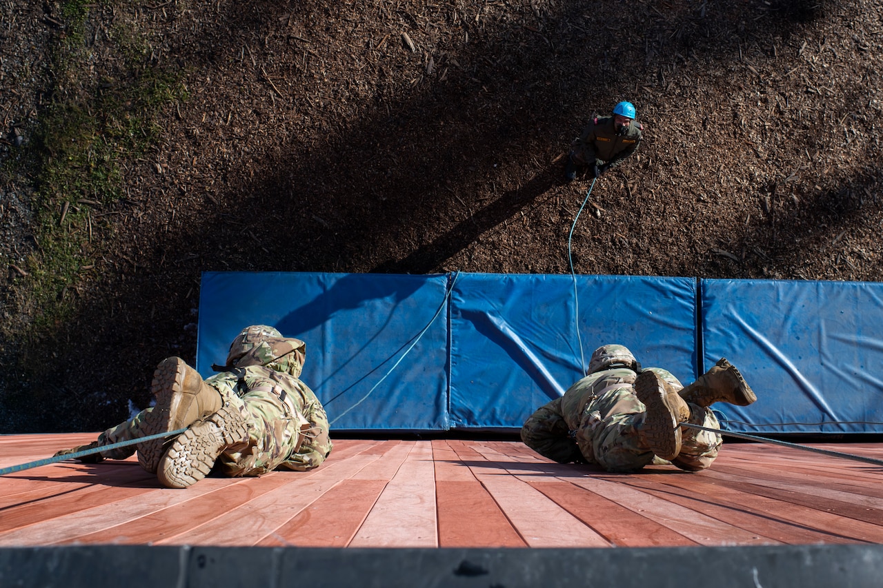 Two soldiers crawl down a wall.
