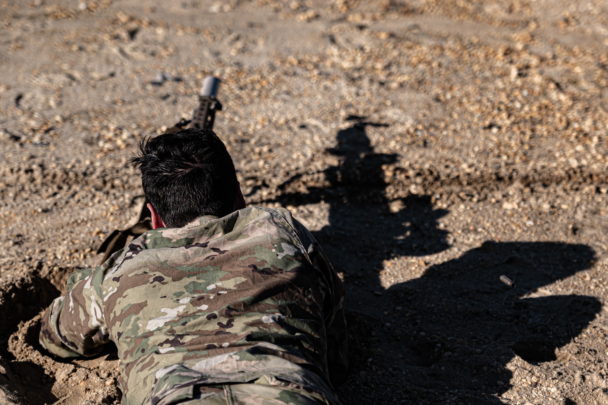 Soldier lays in prone as he aims a rifle