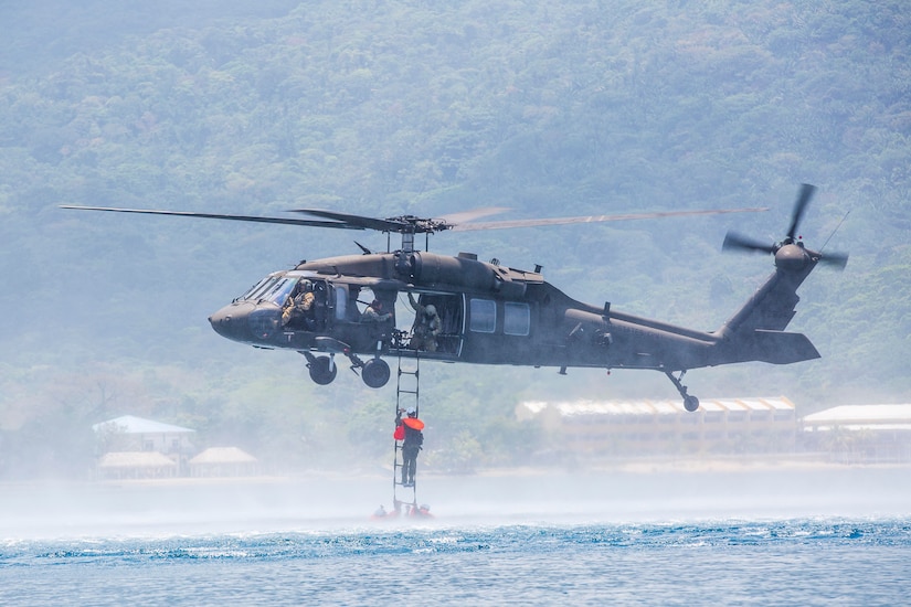 A helicopter hovers over a body of water.