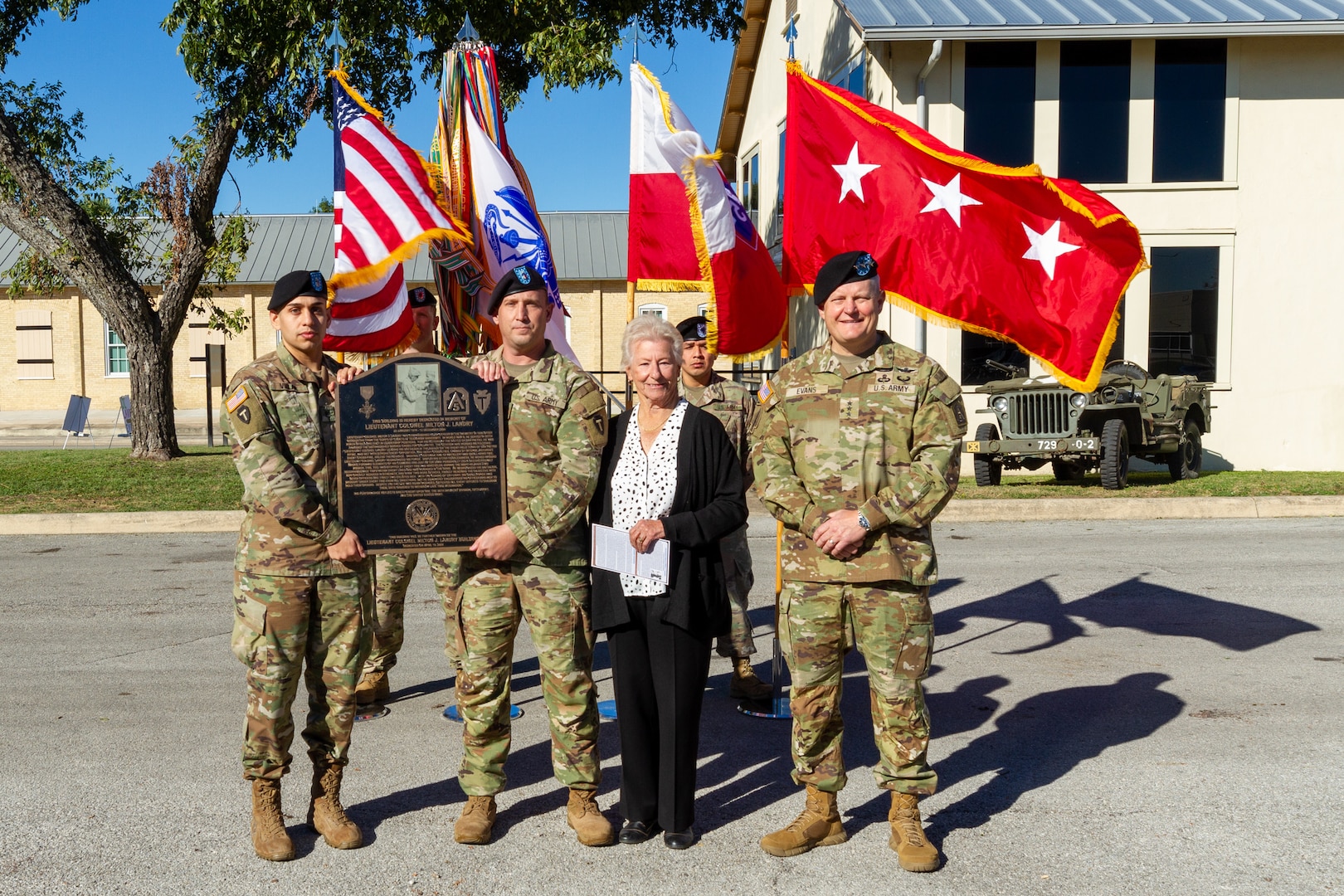 Service members holding plaque standing by a woman and Army General.