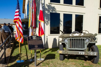 Building, memorial plaque and Army vehicle.
