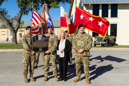 Service members holding plaque standing by a woman and Army General.