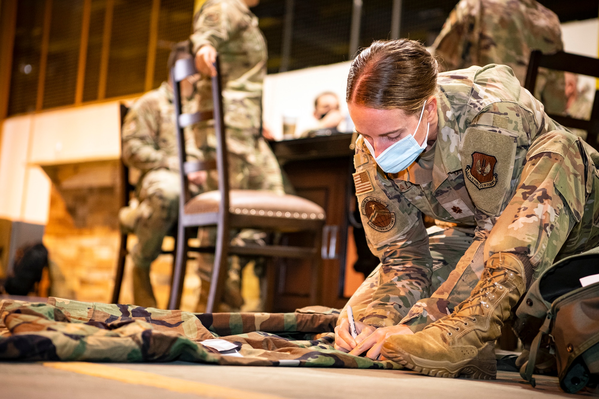 U.S. Air Force Maj. Erica Balfour, 423d Communications Squadron commander, writes on her Mission Oriented Protective Posture gear prior to Ability to Survive and Operate training at RAF Alconbury, England, Aug. 27, 2021. The ATSO rodeo was designed to reinforce Airmen’s ability to properly utilize their MOPP gear in a potential chemical environment. (U.S. Air Force photo by Senior Airman Eugene Oliver)