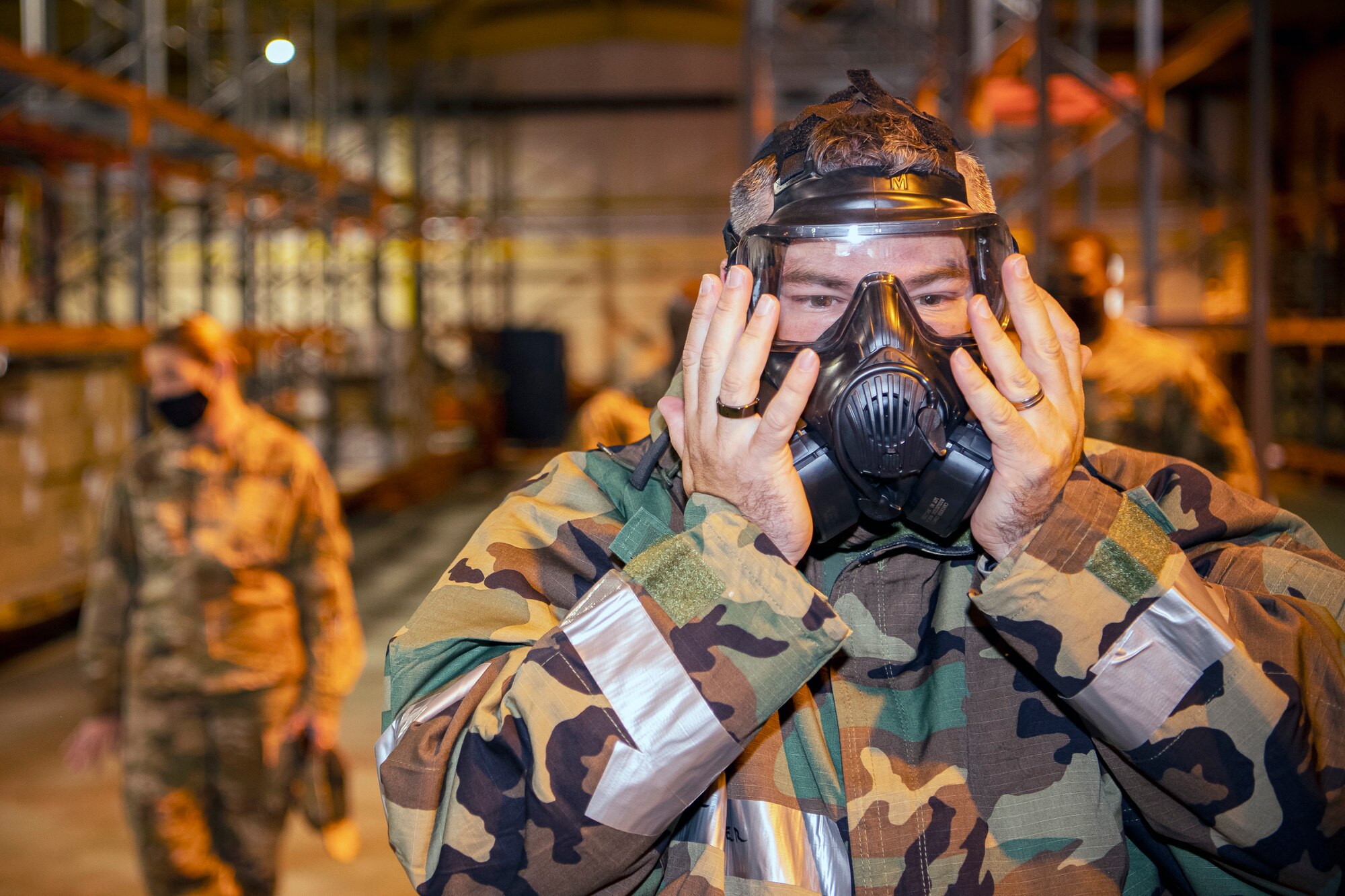 U.S. Air Force Col. Brian Filler, right, 501st Combat Support Wing commander, performs a seal check on his gas mask during Ability to Survive and Operate training at RAF Alconbury, England, Aug. 27, 2021. Filler along with other Airmen from the 501st CSW participated in the ATSO rodeo to get a refresher on how to properly utilize their MOPP gear in a potential chemical environment. (U.S. Air Force photo by Senior Airman Eugene Oliver)
