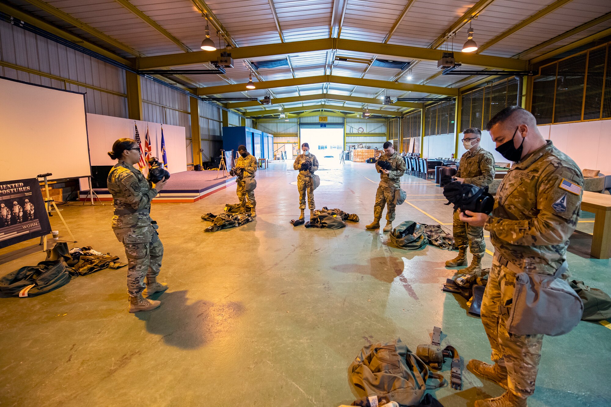 U.S. Air Force Staff Sgt. Ashley Ortiz, left, 423d Civil Engineer Squadron emergency manager, gives instruction on how to don a gas mask during Ability to Survive and Operate training at RAF Alconbury, England, Aug. 27, 2021. The ATSO rodeo was designed to reinforce Airmen’s ability to properly utilize their MOPP gear in a potential chemical environment. (U.S. Air Force photo by Senior Airman Eugene Oliver)