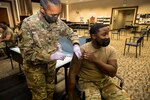 Service member administers COVID-19 vaccine to fellow service member