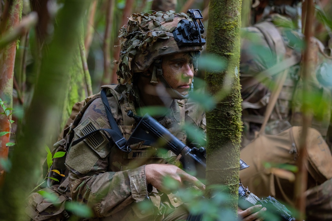 Soldiers carrying weapons train in a jungle environment.
