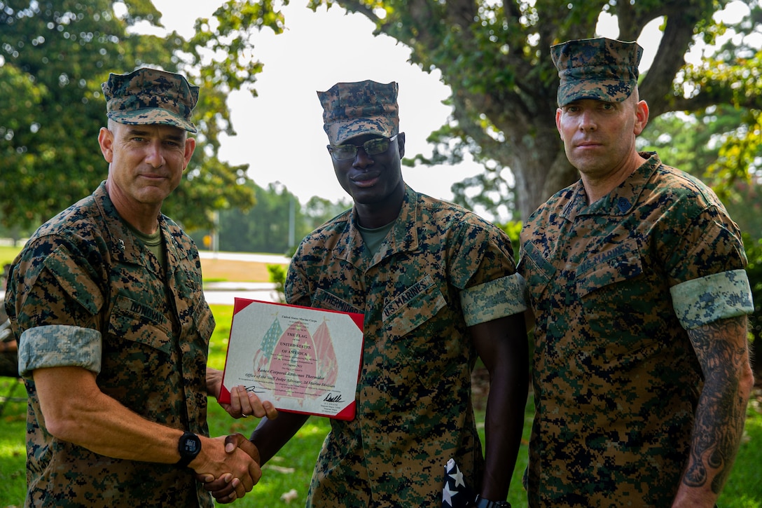 U.S. Marine Corps Maj. Gen. Francis Donovan, left, commanding general, Lance Cpl. Anthonas Thermidor, center, a legal services specialist with Headquarters Battalion, and Sgt. Maj. Daniel Krause, right, sergeant major, all with 2d Marine Division, pose for a photo after a flag presentation ceremony at Camp Lejeune, N.C., Aug. 27, 2021. Thermidor, a Haitian native, received an American flag to commemorate earning American citizenship. (U.S. Marine Corps photo by Lance Cpl. Eric Rodriguez)