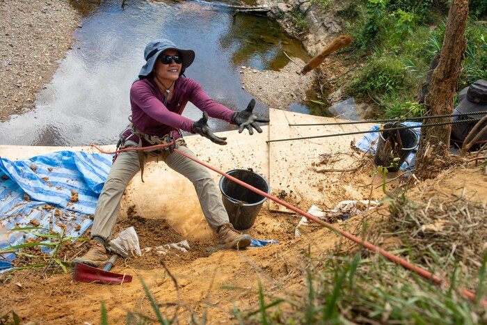 U.S. Space Force Master Sgt. Hanh Le, a Defense POW/MIA Accounting Agency recovery team linguist, prepares to catch a bucket during a recovery mission in Quang Nam Province, Vietnam, June 29, 2021. DPAA’s mission is to achieve the fullest possible accounting for missing and unaccounted-for U.S. personnel to their families and our nation. (U.S. Air Force photo by Staff Sgt. Jonathan McElderry)