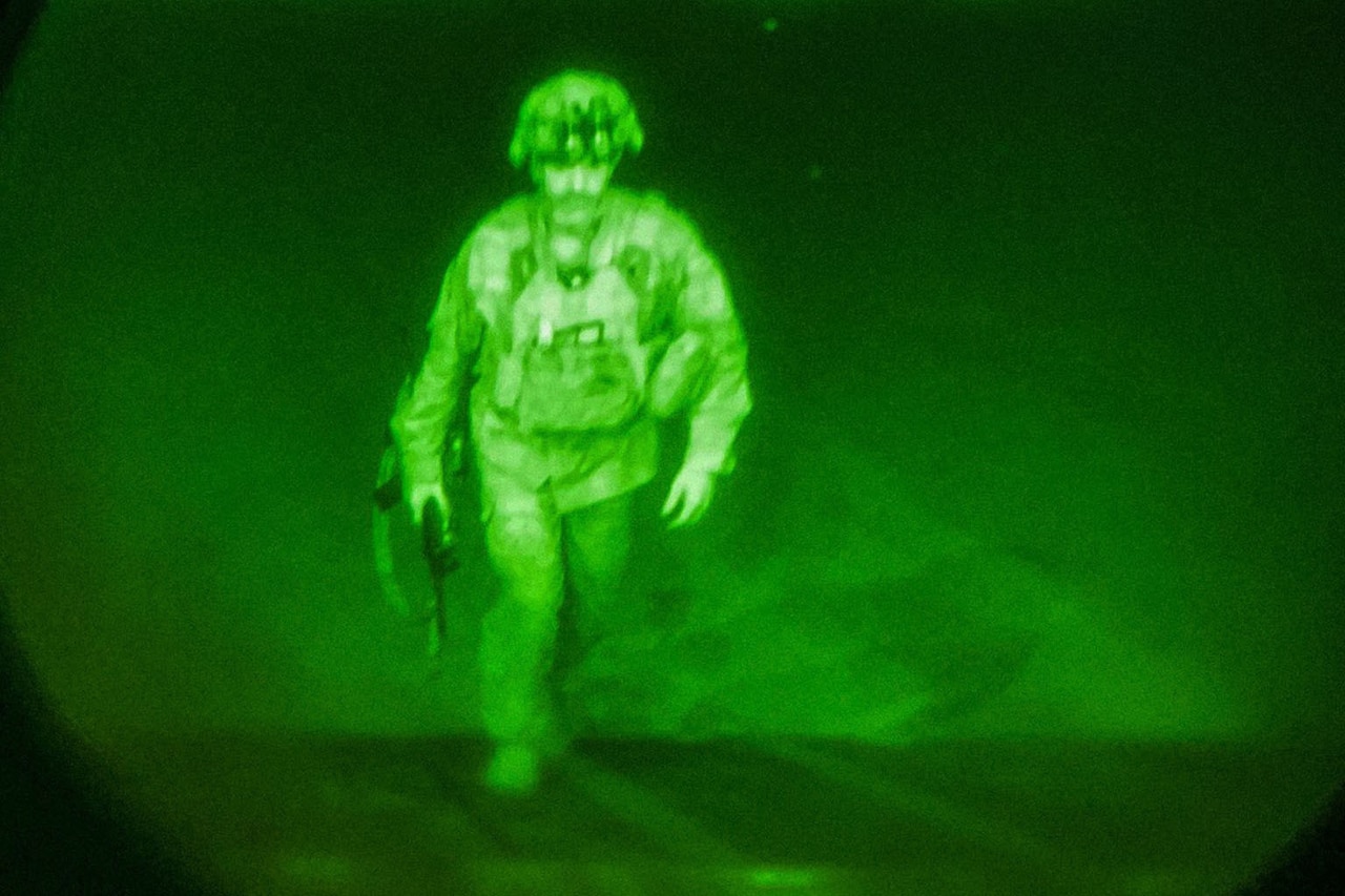 Seen through a night vision lens, a soldier walks up a ramp on a flightline.