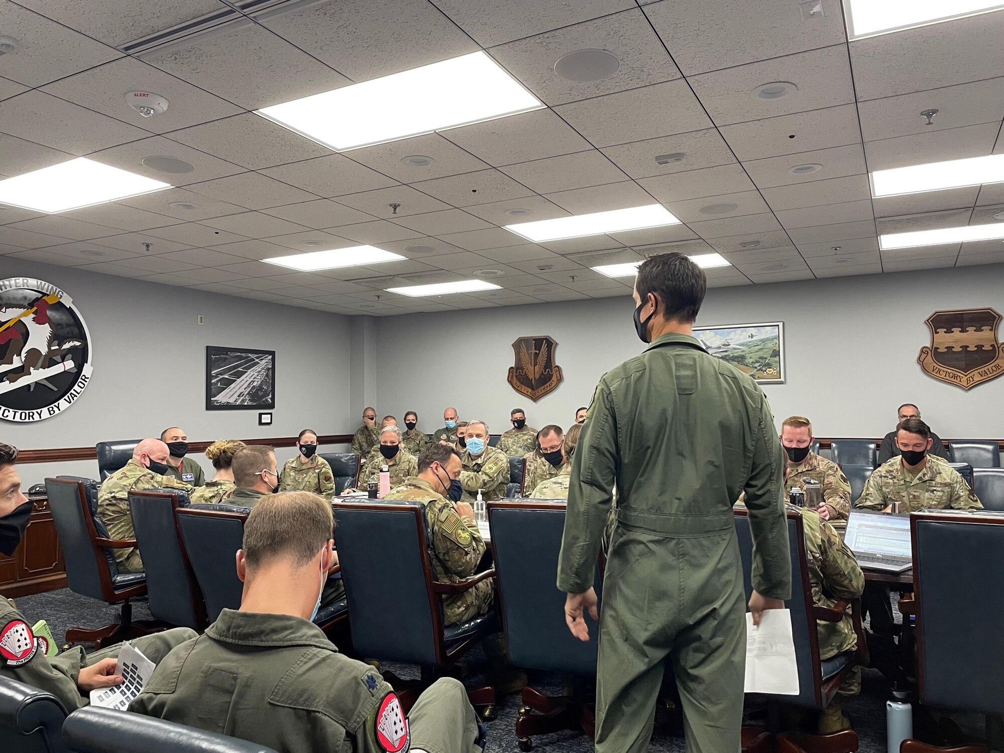 Photo of U.S. Air Force Airmen standing in front of a group of Airmen sitting at a table