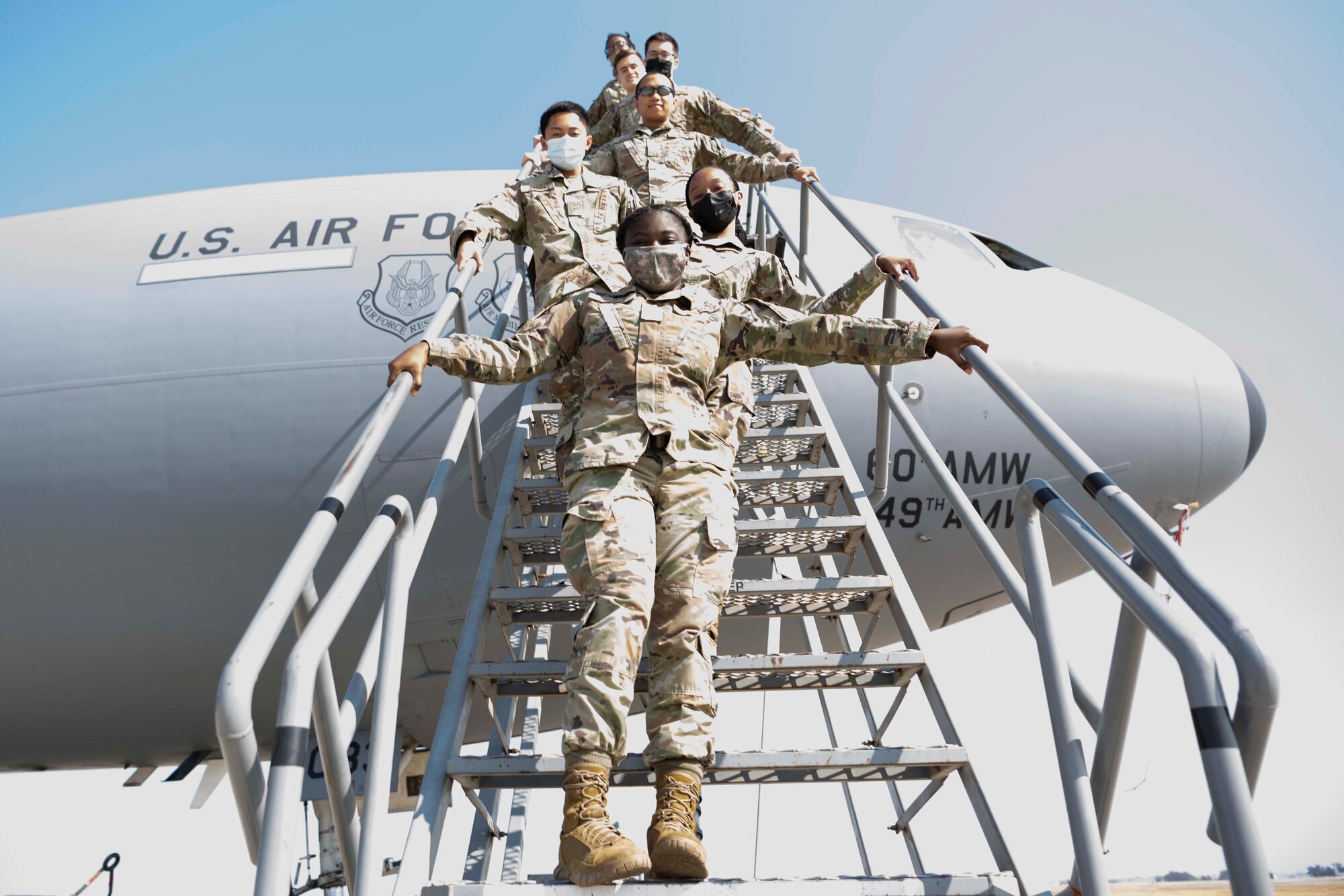 Airmen pose for photo on stairs of an aircraft