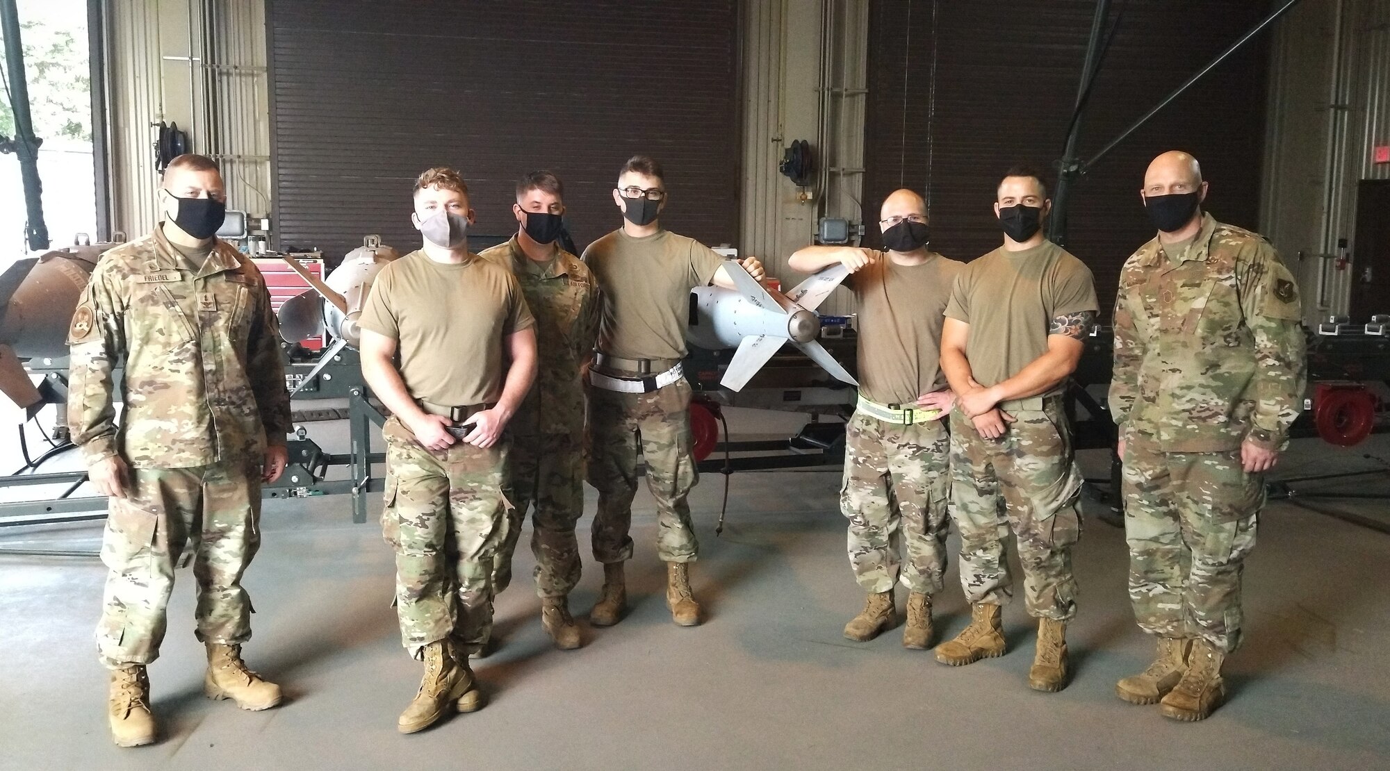 People in a camo uniform work around large cylindrical munitions