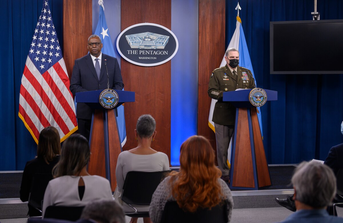 Two men brief members of the media.