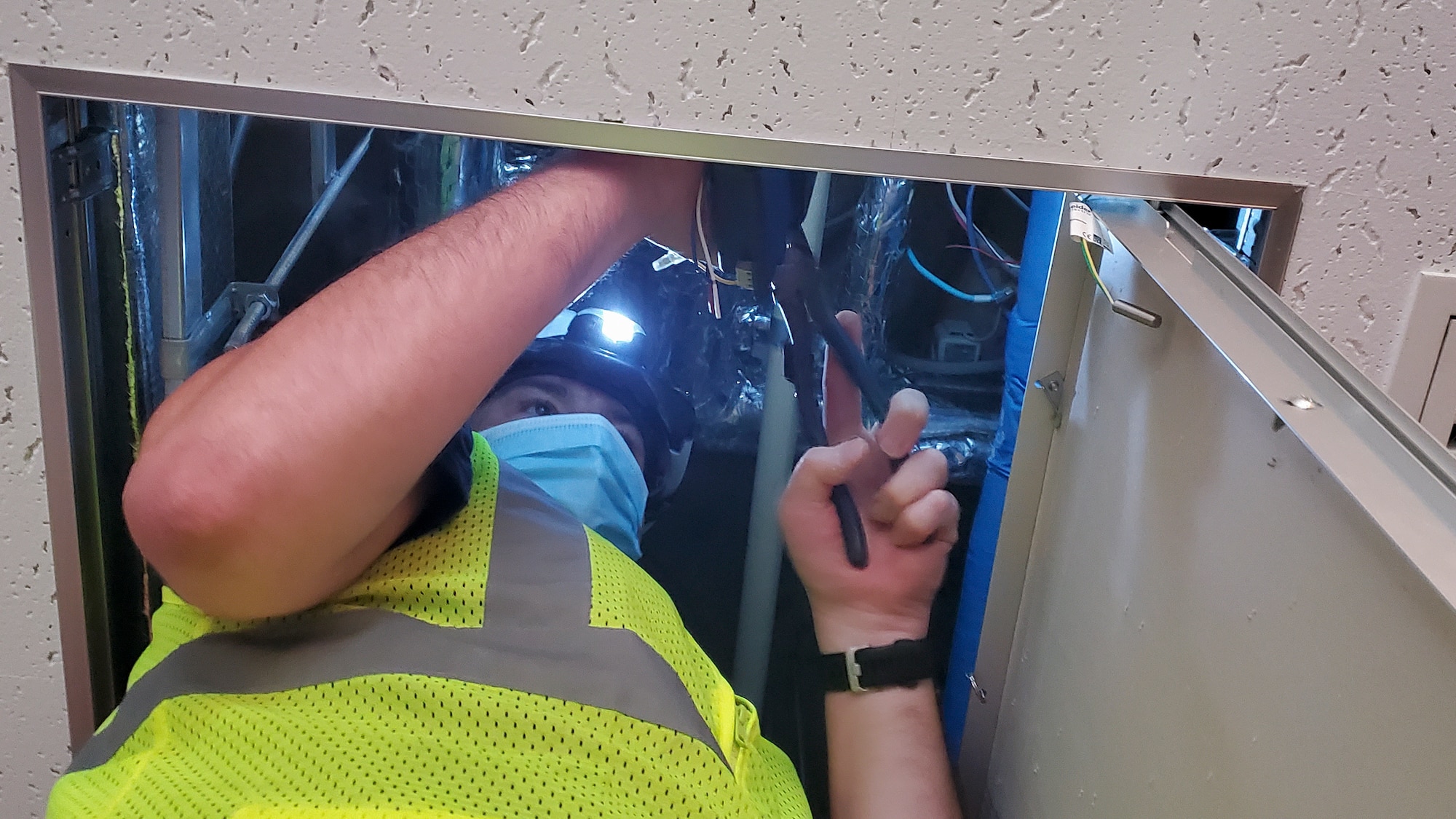 contractor works on wiring running across a facility’s ceiling fixtures