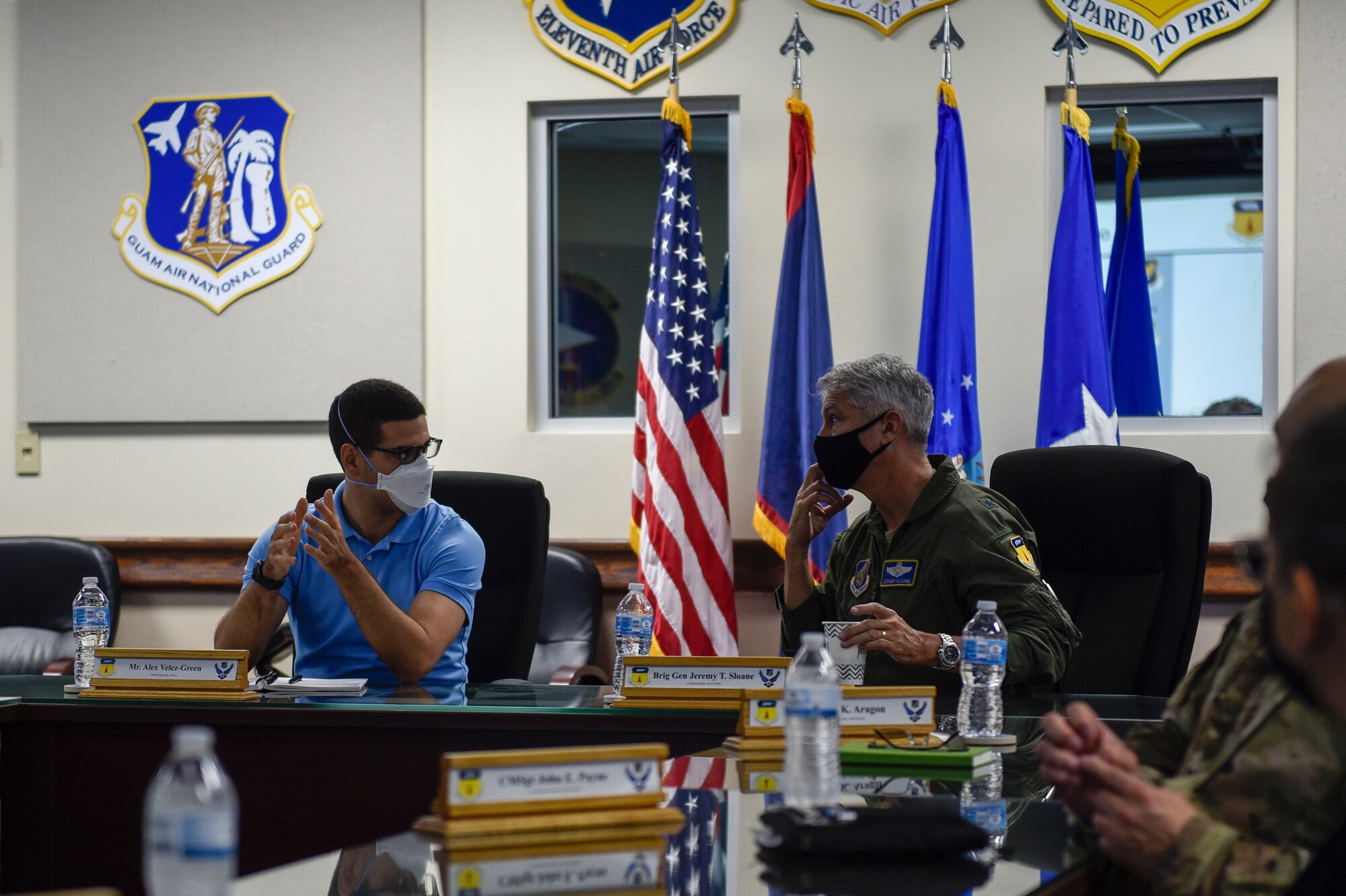 Two people talking at the head of a table.