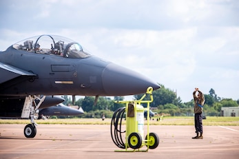 Airman 1st Class Kevaughn Kerr, right, 48th Aircraft Maintenance Squadron crew chief, marshals an F-15E Strike Eagle assigned to the 492d Fighter Squadron during an Agile Combat Employment exercise at RAF Fairford, England, Aug. 23, 2021. The exercise enables U.S. forces in Europe to operate from locations with varying levels of capacity and support. This further ensures Airmen and aircrews are postured to deliver lethal combat power across the full spectrum of military operations. (U.S. Air Force photo by Senior Airman Eugene Oliver)