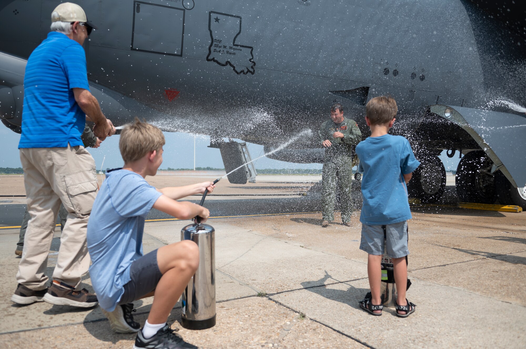 Three people spray liquid at another person.