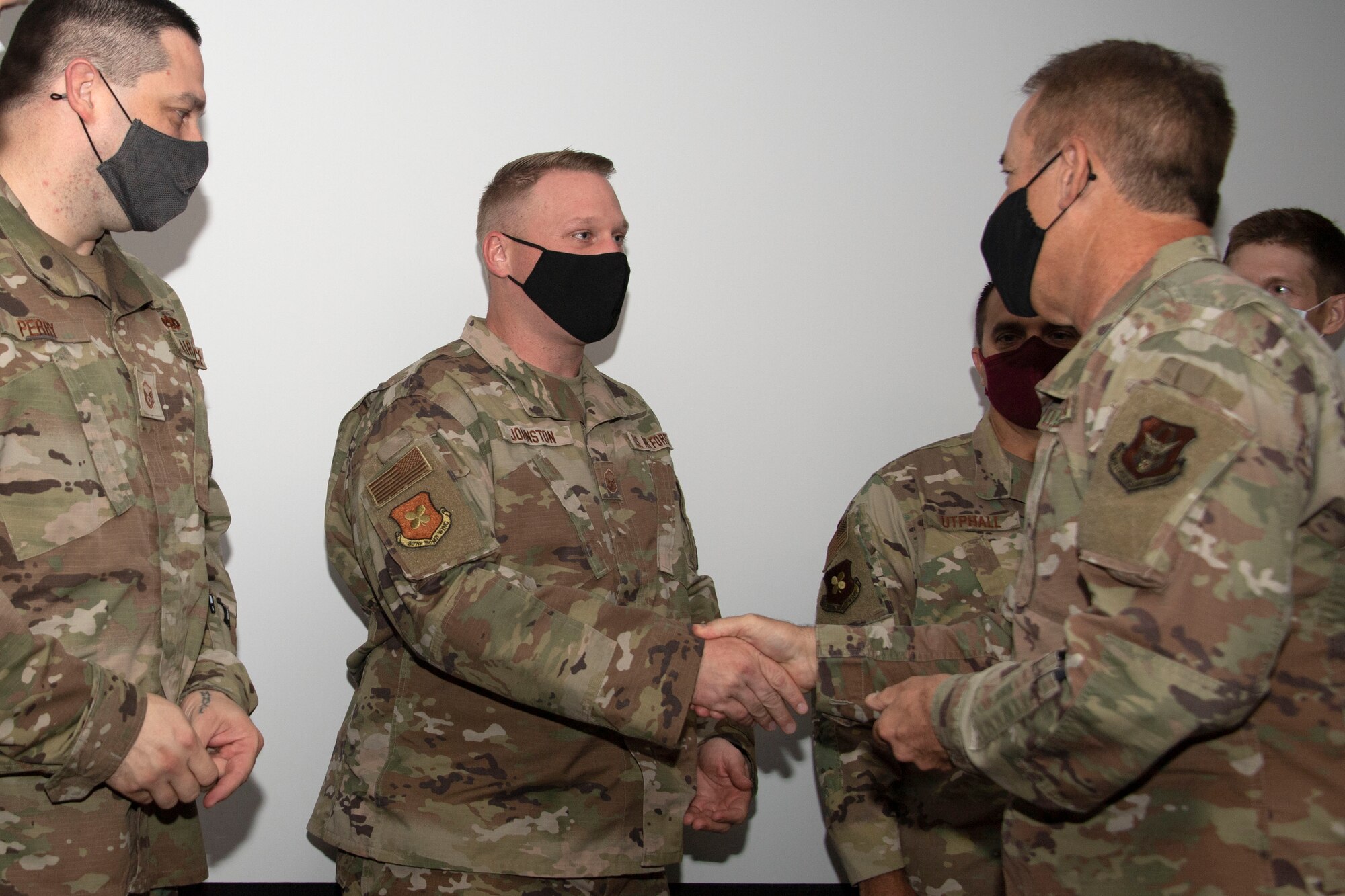 Two men shaking hands as three others watch.