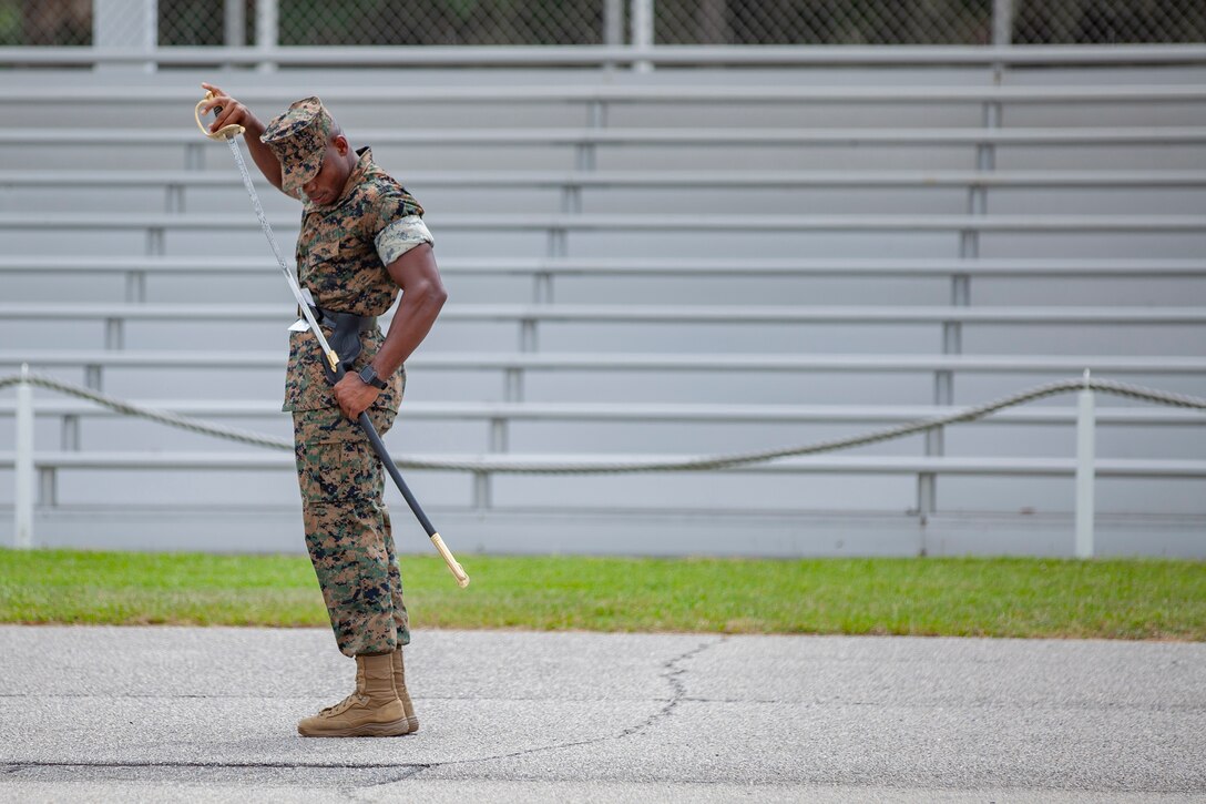 A Marine stands as he puts his sword in a scabbard.