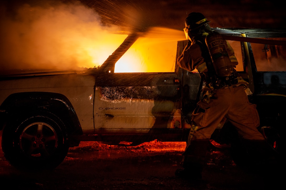 An airman works to put out a car fire.