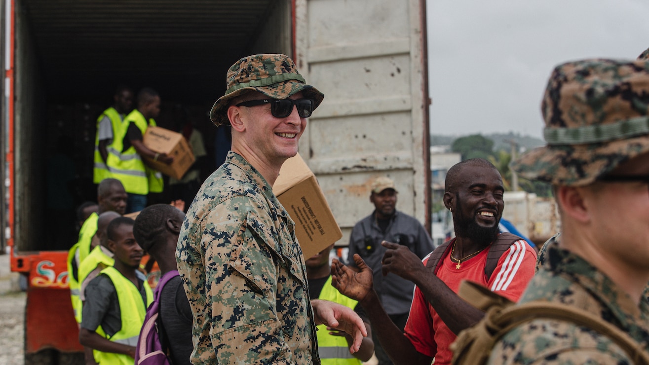 U.S. Marine Corps Capt. Steven Fleming, a native of Egg Harbor Township, N.J., and a forward air controller with 1st Battalion, 6th Marine Regiment, 2d Marine Division, helps offload boxes for redistribution with local volunteers in Port of Jeremie, Haiti, Aug. 31, 2021.  “It is very rewarding to be here and offer support to those in need,” Fleming said. The Marines and sailors aboard the USS Arlington (LPD 24) have been serving in support of Joint Task Force-Haiti for a humanitarian assistance and disaster relief mission. “I am so proud of the commitment our Marines demonstrated today. Nearly two weeks ago, these Marines deployed with less than 12 hours notice to answer the nation’s call and serve as a force in readiness for the Joint Task Force. Today, we were able to put boots on the ground and work side-by-side with sailors and local volunteers to distribute aid to areas most impacted by the earthquake. There is truly no better friend than a United States Marine.” (U.S. Marine Corps photo by Lance Cpl. Jacqueline C. Arre)