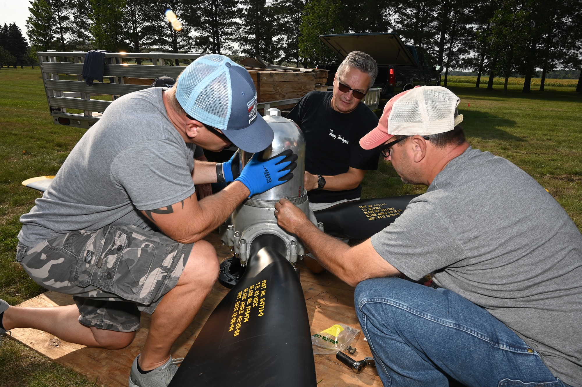Three men assemble a B-25 propeller for display on the grassy grounds of the North Dakota Veterans Home, Lisbon, N.D., Sept., 1, 2021.