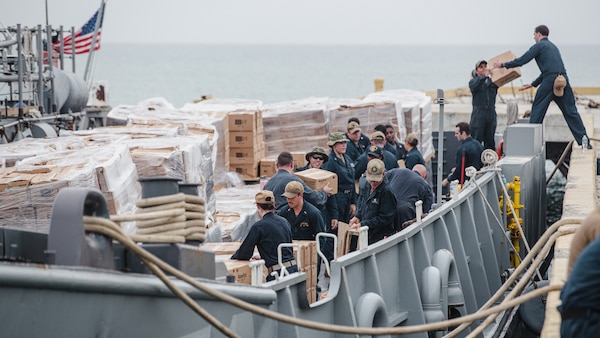 U.S. Marines and Sailors with Joint Task Force-Haiti (JTF-Haiti) and volunteers help offload boxes for redistribution in Port of Jeremie, Haiti.