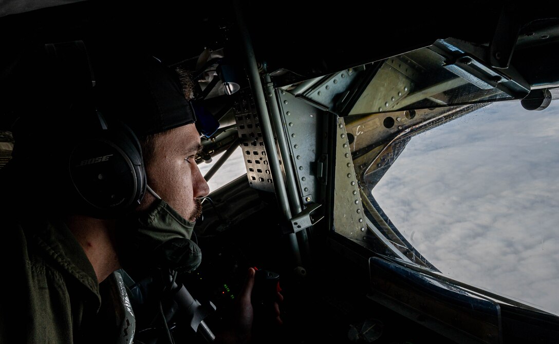 An Airman prepares to refuel a jet mid-air.