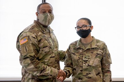 Sgt. Maj. Darnell Cabell, senior enlisted leader and principle advisor to the military deputy to the Assistant Secretary of the Army for Financial Management and Comptroller, presents his challenge coin for excellence to Spc. Meriah Rudie, 376th Financial Management Support Detachment financial management technician, during Diamond Saber at Fort McCoy, Wisconsin, Aug. 17, 2021. Diamond Saber is a U.S. Army Reserve-led exercise that incorporates all Army components and joint services, and it prepares finance and comptroller Soldiers on warfighting functions such as funding the force, payment support, disbursing operations, accounting, fiscal stewardship, auditability and data analytics. (U.S. Army photo by Mark R. W. Orders-Woempner)