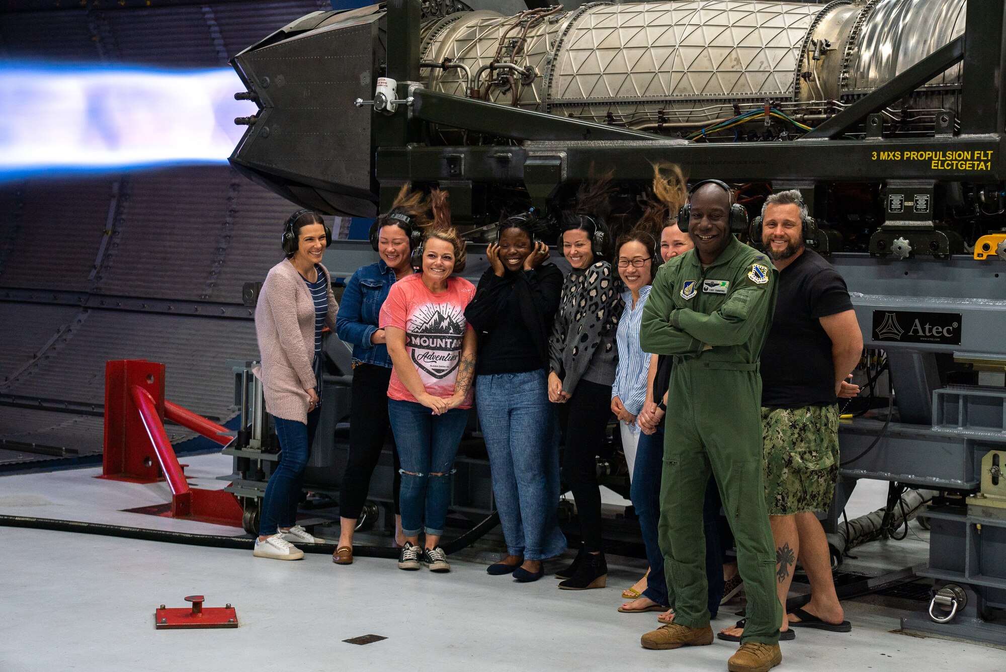 U.S. Air Force Col. Travolis Simmons, the 3rd Wing commander, stands with 3rd Wing spouses next to a running F-22 Raptor engine during an immersion tour on Joint Base Elmendorf-Richardson, Alaska.